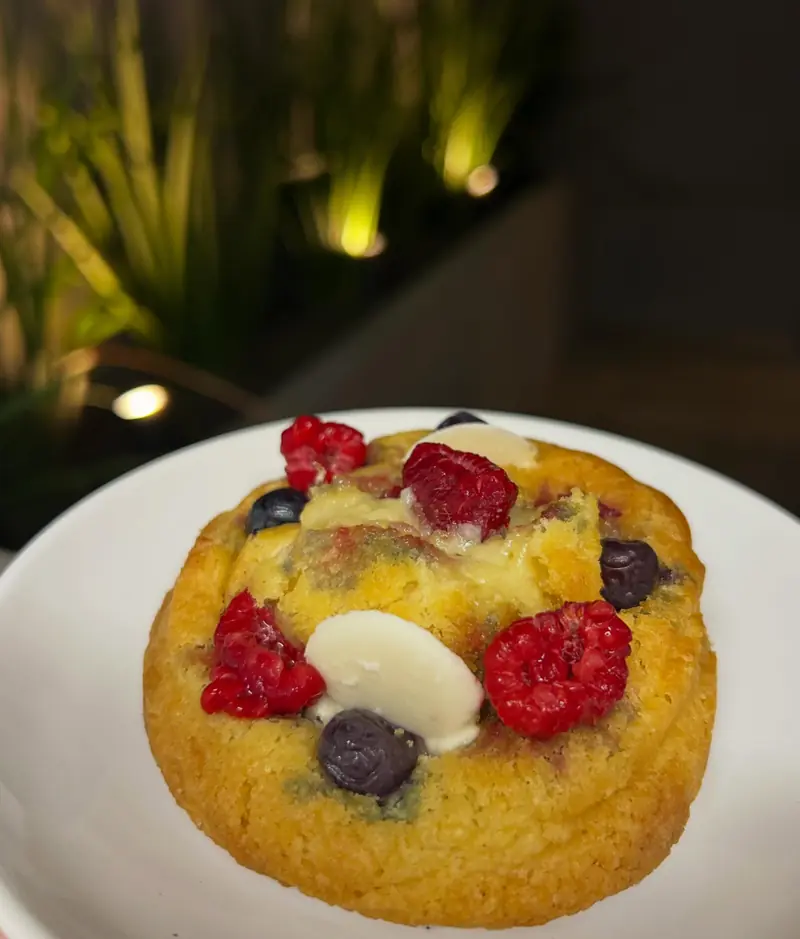Cookie rellena con frutos rojos y chocolate blanco, en plato blanco