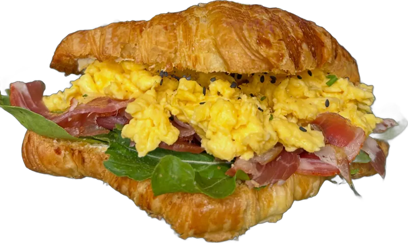 Croissant relleno de huevos revueltos, jamón crudo y rúcula